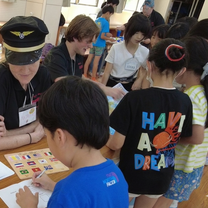 Intern interacting with a small group of Japanese children as the children complete a fun activity in English.