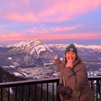 Woman pointing at a snowy mountain at sunset