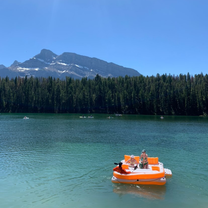 People on an inflatable on a blue lake with mountains in the background