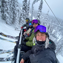 Four people on a ski lift in the snow