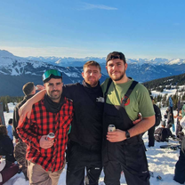 Three men standing at the top of a snowy mountain
