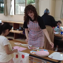 Intern interacting with a Japanese child as the child orders from her play restaurant during an English language exercise.