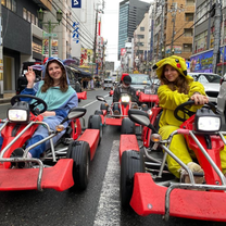 Two women in onsies in go karts on the streets of Tokyo