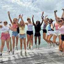 A group of girls jumping on a pier next to the ocean in Belize