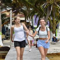 Two friends walking together and laughing on a boardwalk in Belize.