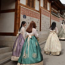 A group of girls dressed in traditional Korean Hanbok walk the streets of Seoul.