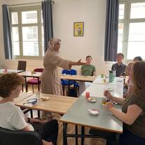 Students gather in a bright classroom for an engaging group discussion and traditional Moroccan tea experience, guided by an instructor.