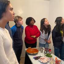 Immersive learning at Hikayat: A diverse group of students eagerly looks on during a Moroccan cooking class, ready to prepare a traditional tagine with fresh ingredients.