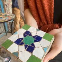 A student proudly displays their finished piece from our immersive Moroccan Zellij workshop. This intricate, eight-pointed geometric star was handcrafted using traditional techniques, connecting art, history, and Moroccan culture in one beautiful object.