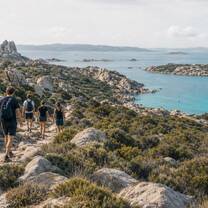 Illustrative image of a group hiking along Sardinia's rocky coastline
