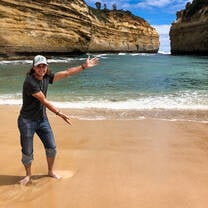 A man with arms stretched our showing the water of the great ocean road