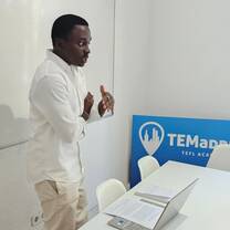 A participant presents beside a whiteboard and TEFL Madrid sign.