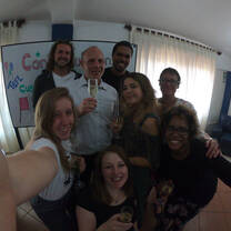 People smiling together with stemmed glasses in front of a decorated whiteboard.