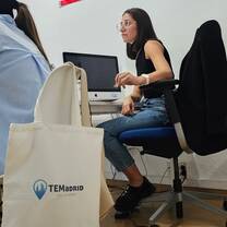 A participant listens during a classroom session with a TEFL Madrid tote bag nearby.
