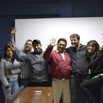 A group posing with raised hands in front of a whiteboard.