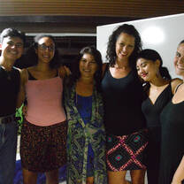 Six people smiling together beside a whiteboard.