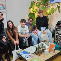 Five people sit together in the academy lounge, with plants and books nearby.