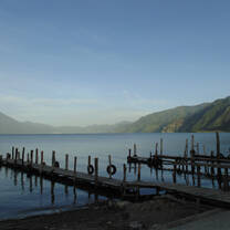 Wooden piers along a blue lake with mountains beyond.