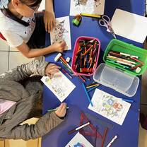 Kids drawing at a table with colorful pencils, during their class in divino niño