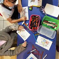 Kids drawing at a table with colorful pencils, during their class in divino niño