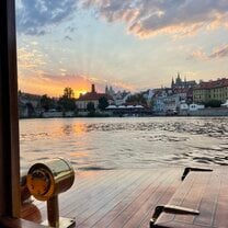 view of sunset behind Petřín and Prague Castle from a cruise on river Vltava