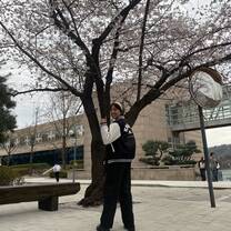 On campus photo wearing the school's leather man jacket during the early bloom of the cherry blossoms 
