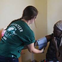 Projects Abroad intern checks blood pressure of a woman in Kenya