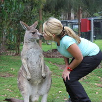 girl kneeling down to kiss kangaroo