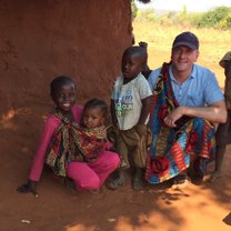 Man in Zambia with four kids crouching down outside