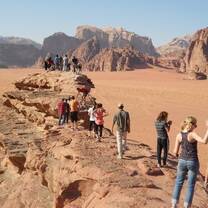 A long line of people walking on large rocks in Jordan