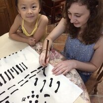 Au pair is writing Chinese with kid  teacher writing chinese with a kid