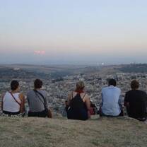Students sitting atop a hill overlooking a city