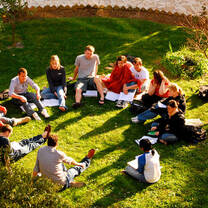 Students sit in the grass in a circle