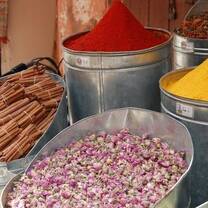 Four metal buckets with colorful spices in a market