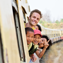 children and teacher smiling and leaning out of a train window