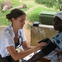 A Nurse volunteer helping to Check the temperature of the sick old