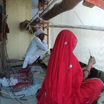 A rural poor couple weaving carpet at their door step