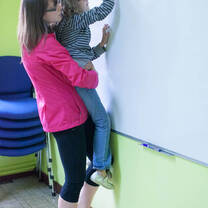 English teacher helps a student write on the board in Russia, Jun 2013