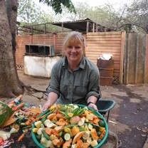 A volunteer smiling at a wildlife rehabilitation center with food before feeding time.