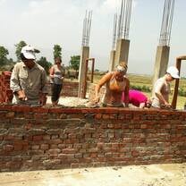 Volunteers and local workers building a classroom wall