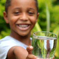 A young boy just filled up his cup with clean water from the faucet in his home.